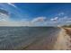A tranquil beach view with clear water, a sandy shoreline, and cloudy skies at 1647 Hamilton Ct, Dunedin, FL 34698