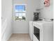 Bright laundry room with washer, dryer, large window and storage shelf at 16633 Goose Ribbon Pl, Wimauma, FL 33598