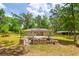 Backyard of a single-Gathering home featuring a brick firepit, patio and lush green trees at 19266 Campground Rd, Brooksville, FL 34601