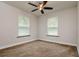 Well-lit bedroom features plush carpeting, a ceiling fan, and two windows offering plenty of natural light at 19266 Campground Rd, Brooksville, FL 34601