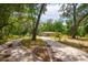 Charming single-story home featuring a cozy facade and a long driveway surrounded by mature trees and lush greenery at 19266 Campground Rd, Brooksville, FL 34601