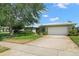 Charming single-story home featuring a well-manicured front yard, a two-car garage, and mature trees at 2060 Attache Ct, Clearwater, FL 33764