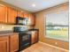 Compact kitchen with wood cabinets, black appliances, and natural light, ideal for everyday meal preparation at 2453 Edgewater Falls Dr, Brandon, FL 33511