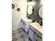 Modern bathroom featuring dual vanities, round mirrors, and stylish patterned tile floors at 3532 Overland Dr, Holiday, FL 34691