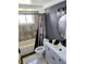 This bathroom features gray flooring and shower tiles, updated vanity, toilet, and shower/tub with curtain at 3532 Overland Dr, Holiday, FL 34691