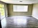 Bright living room with wood-look tile floors, sliding glass door, and a large window offering plenty of natural light at 3532 Overland Dr, Holiday, FL 34691