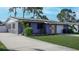 Single-story home with solar panels, a vibrant yellow door, and a well-kept lawn in a sunny neighborhood at 4511 Huntington Ne St, St Petersburg, FL 33703