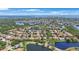This aerial shows a community with a pond, surrounded by trees, houses, and a distant view of the ocean at 4815 Queen Palm Ne Ter, St Petersburg, FL 33703