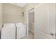 Laundry room with modern white washer and dryer, storage shelf and doorway at 7410 S Fitzgerald St, Tampa, FL 33616