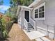 Charming front entry with a gray exterior, white stairs, and well-maintained landscaping at 8114 N 11Th St, Tampa, FL 33604
