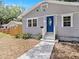 Close-up view of a charming single-story home showcasing a blue door and tidy front yard at 8114 N 11Th St, Tampa, FL 33604