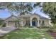 Charming single-story home featuring a well-manicured lawn, blue front door, and an attached two-car garage at 1069 Captains Way, Tarpon Springs, FL 34689
