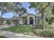 Charming single-story home featuring a well-manicured lawn, blue front door, and an attached two-car garage at 1069 Captains Way, Tarpon Springs, FL 34689