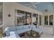 Relaxing covered patio with comfortable seating, ceiling fan, and access to the screened-in pool area at 1069 Captains Way, Tarpon Springs, FL 34689
