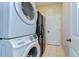 A laundry room featuring a stacked washer/dryer and black refrigerator at 11427 Laurel Brook Ct, Riverview, FL 33569
