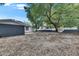 Spacious backyard featuring mature trees, gravel landscaping, concrete slab, and partial fencing at 1208 E 18Th Ave, Tampa, FL 33605