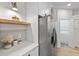 Bright kitchen with stainless steel refrigerator and white cabinets, leading to a laundry room at 12531 Blazing Star Dr, Tampa, FL 33626