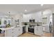 Modern white kitchen with stainless steel appliances, island with seating, and view to a dining area at 12531 Blazing Star Dr, Tampa, FL 33626