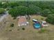 Expansive aerial view of the property with a pool, sheds, and surrounding greenery at 13208 Sydney Rd, Dover, FL 33527