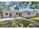 Exterior view of a modern home with a stone patio, manicured lawn, and mature trees at 1401 49Th N St, St Petersburg, FL 33710