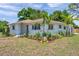 Charming home with manicured lawn and lush landscaping, complemented by young palm trees and vibrant flowerbeds at 1401 49Th N St, St Petersburg, FL 33710