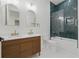 Modern bathroom boasts a double vanity with wood cabinets and a shower with striking green tile at 1542 Bayshore Blvd, Dunedin, FL 34698