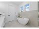 Modern bathroom featuring a soaking tub, neutral tile, and bright windows for natural lighting at 1542 Bayshore Blvd, Dunedin, FL 34698