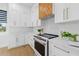 Contemporary kitchen featuring modern appliances, white cabinetry, and unique wooden range hood at 1542 Bayshore Blvd, Dunedin, FL 34698