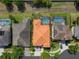 Aerial view of house with an orange roof, a screened-in pool, and surrounding houses and grass at 15630 N Himes Ave, Tampa, FL 33618