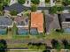 Overhead view of house with an orange tile roof with a screened in pool near neighboring houses at 15630 N Himes Ave, Tampa, FL 33618