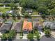 Aerial view of a house with a screened-in pool and an orange tiled roof among green trees and neighboring houses at 15630 N Himes Ave, Tampa, FL 33618