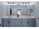 Bathroom with a large mirror, double vanity with gray cabinets, decorative lighting, and sink accessories at 15630 N Himes Ave, Tampa, FL 33618