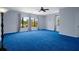 Bedroom with blue carpet, ceiling fan, and large windows with tree top views at 15630 N Himes Ave, Tampa, FL 33618