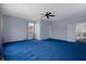 Spacious bonus room with blue carpet, ceiling fan, and natural light from the windows at 15630 N Himes Ave, Tampa, FL 33618