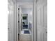 Hallway view of the doors leading to a room and a bathroom with patterned rugs on white tile flooring at 15630 N Himes Ave, Tampa, FL 33618
