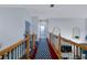 Upstairs hallway with hardwood floors, blue patterned rug, and wood and wrought iron railings at 15630 N Himes Ave, Tampa, FL 33618