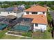 Backyard view of a pool in a screened enclosure and landscaping with orange-tiled roof and surrounding houses at 15630 N Himes Ave, Tampa, FL 33618