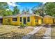 Charming yellow house with a blue door and well-maintained front yard at 1665 Laura St, Clearwater, FL 33755