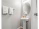 A minimalist half-bath features a pedestal sink, oval mirror, and soft towels at 16930 Red Brick Ln, Land O Lakes, FL 34638