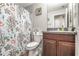 Cozy bathroom features marine themed shower curtain, dark wood vanity, and tile flooring at 16930 Red Brick Ln, Land O Lakes, FL 34638