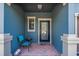 Inviting entryway with a blue accent wall, brick flooring, and a cozy seating area by the black-framed glass door at 16930 Red Brick Ln, Land O Lakes, FL 34638