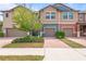 Charming townhome featuring colorful exteriors, manicured landscaping, and a paved driveway leading to attached garages at 16930 Red Brick Ln, Land O Lakes, FL 34638