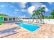A sparkling pool surrounded by an expansive patio, tropical landscaping, and a charming home at 1859 Northview Rd, Largo, FL 33770