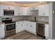 Modern kitchen with white cabinets, stainless steel appliances, granite countertops, tile backsplash, and sleek hardware at 1914 53Rd S St, Gulfport, FL 33707