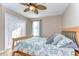 Cozy bedroom with a ceiling fan, patterned bedding, and soft pillows on a wooden bed frame at 19533 Whispering Brook Dr, Tampa, FL 33647