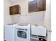 Functional laundry room equipped with a washer, dryer, sink and dark wood cabinets for storage at 19533 Whispering Brook Dr, Tampa, FL 33647