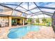 A beautiful screened-in pool area with a custom-shaped pool, brick pavers, and an outdoor kitchen at 19533 Whispering Brook Dr, Tampa, FL 33647