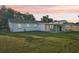 Expansive backyard with lush green lawn and a covered patio during an orange sunset at 2288 Cheryl Rd, Largo, FL 33771