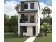 Modern three-story home with a balcony, stucco facade, dark accents, green door, and tropical landscaping at 2309 W Spruce St, Tampa, FL 33607