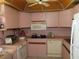 Corner kitchen with pink cabinetry, white appliances, ceiling fan and tile flooring at 2618 Cove Cay Dr # 403, Clearwater, FL 33760